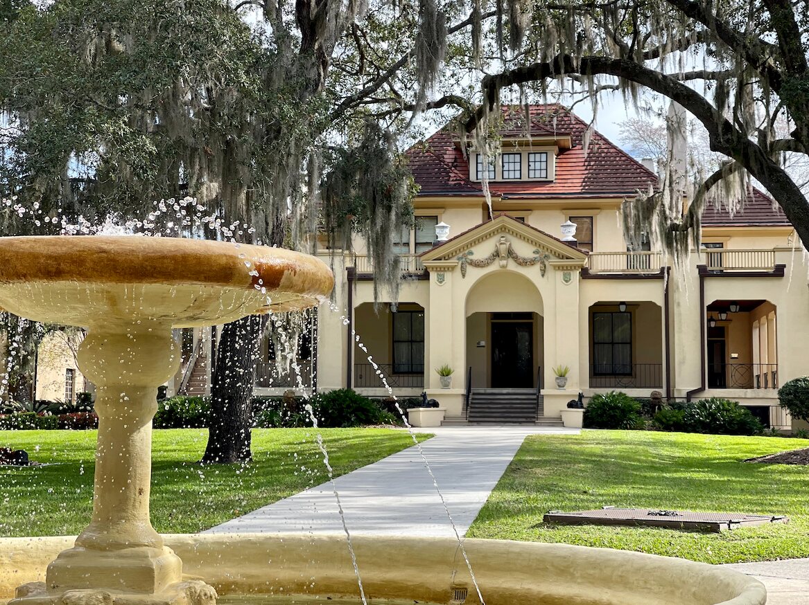 Historic Gainesville building behind a fountain and moss-covered oak trees