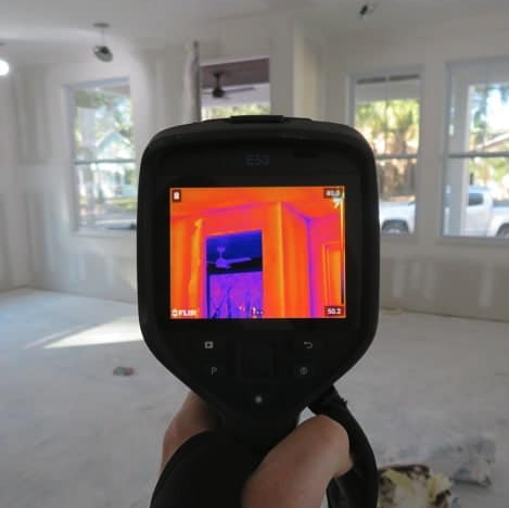 Infrared thermal imaging camera displaying heat variations in a room during home inspection.