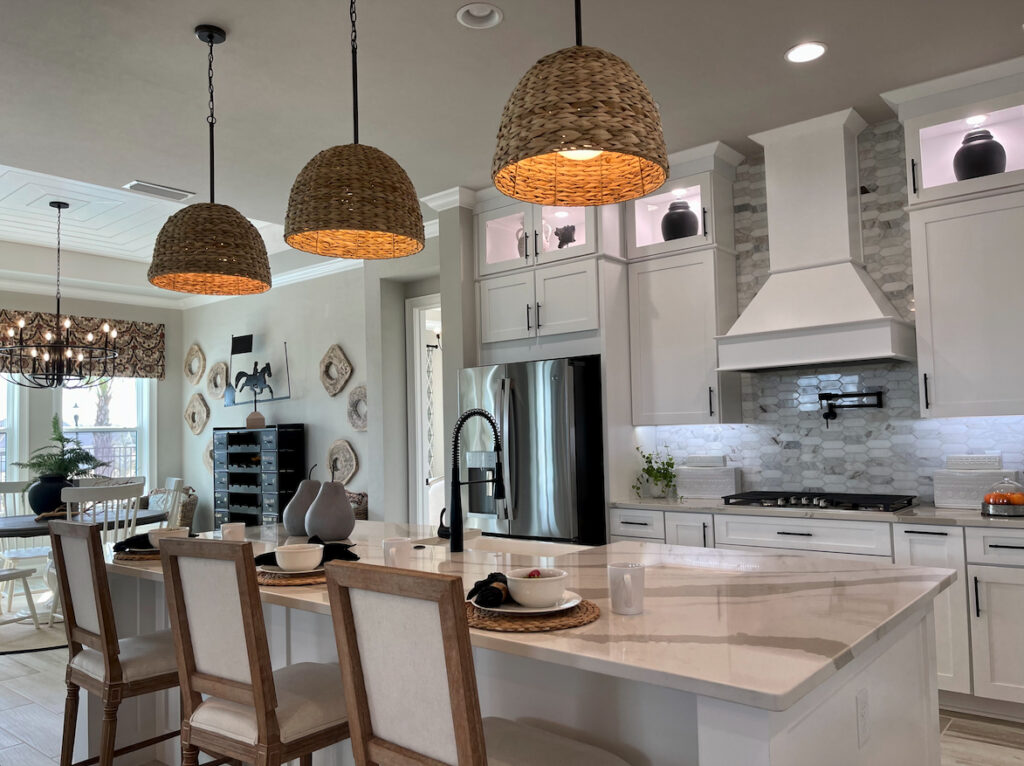 Modern kitchen with white cabinetry, stone backsplash, and woven pendant lights in a Gainesville, FL home for sale.
